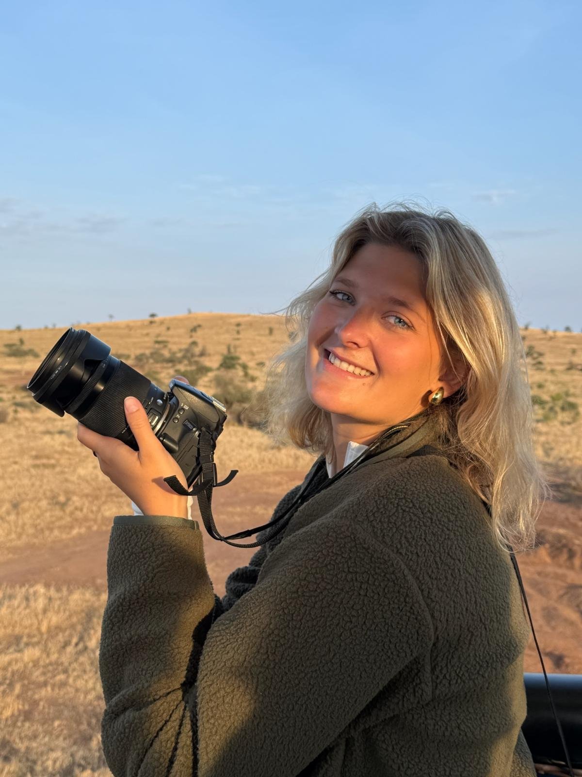 Damasine holding her camera at sunset on the savannah