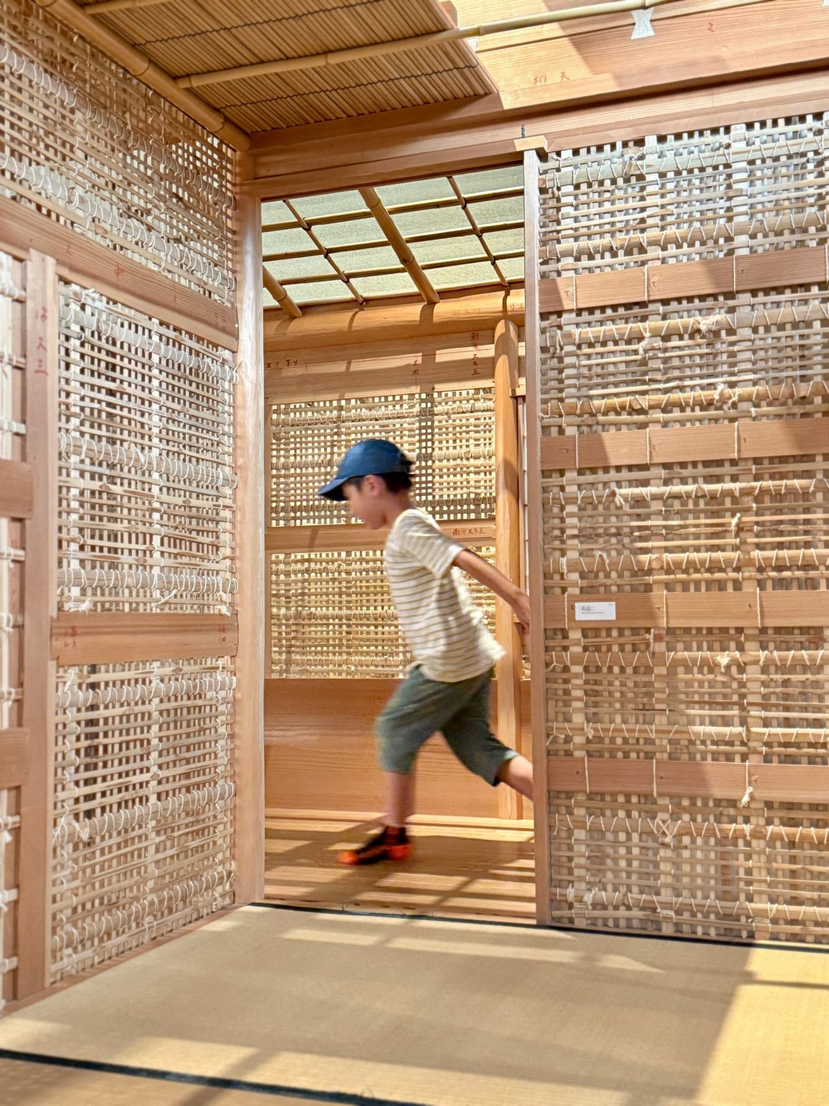 Child running through a woven bamboo pavilion