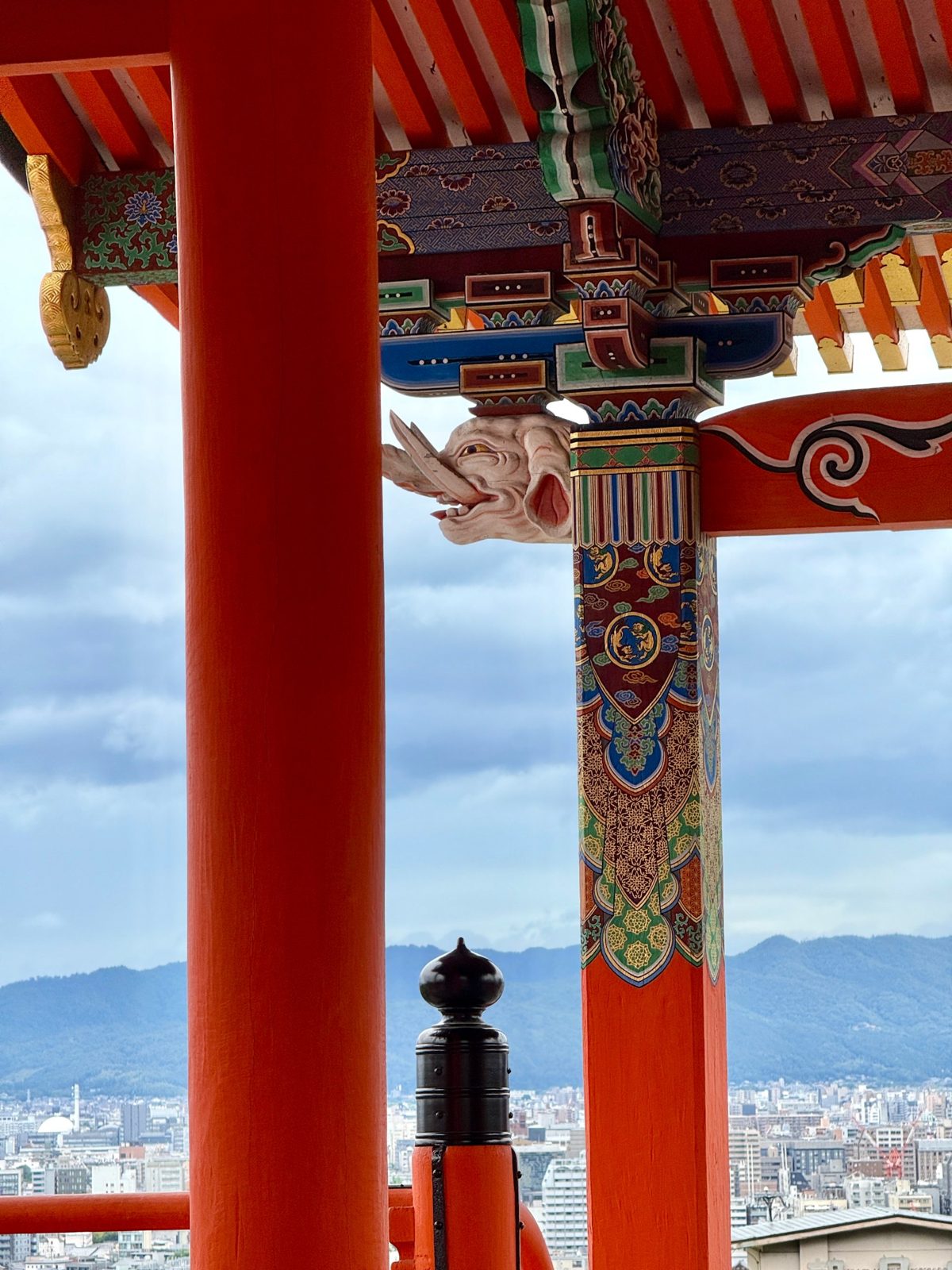 Vermilion temple column with painted brackets above a city