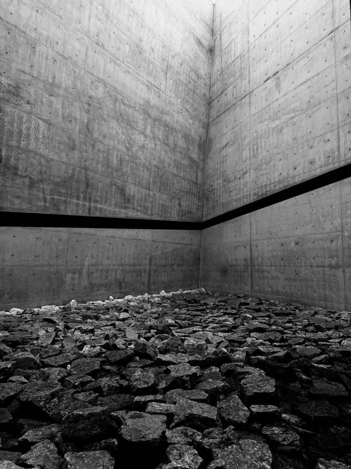 Concrete courtyard with a black slot and a floor of rocks, black and white
