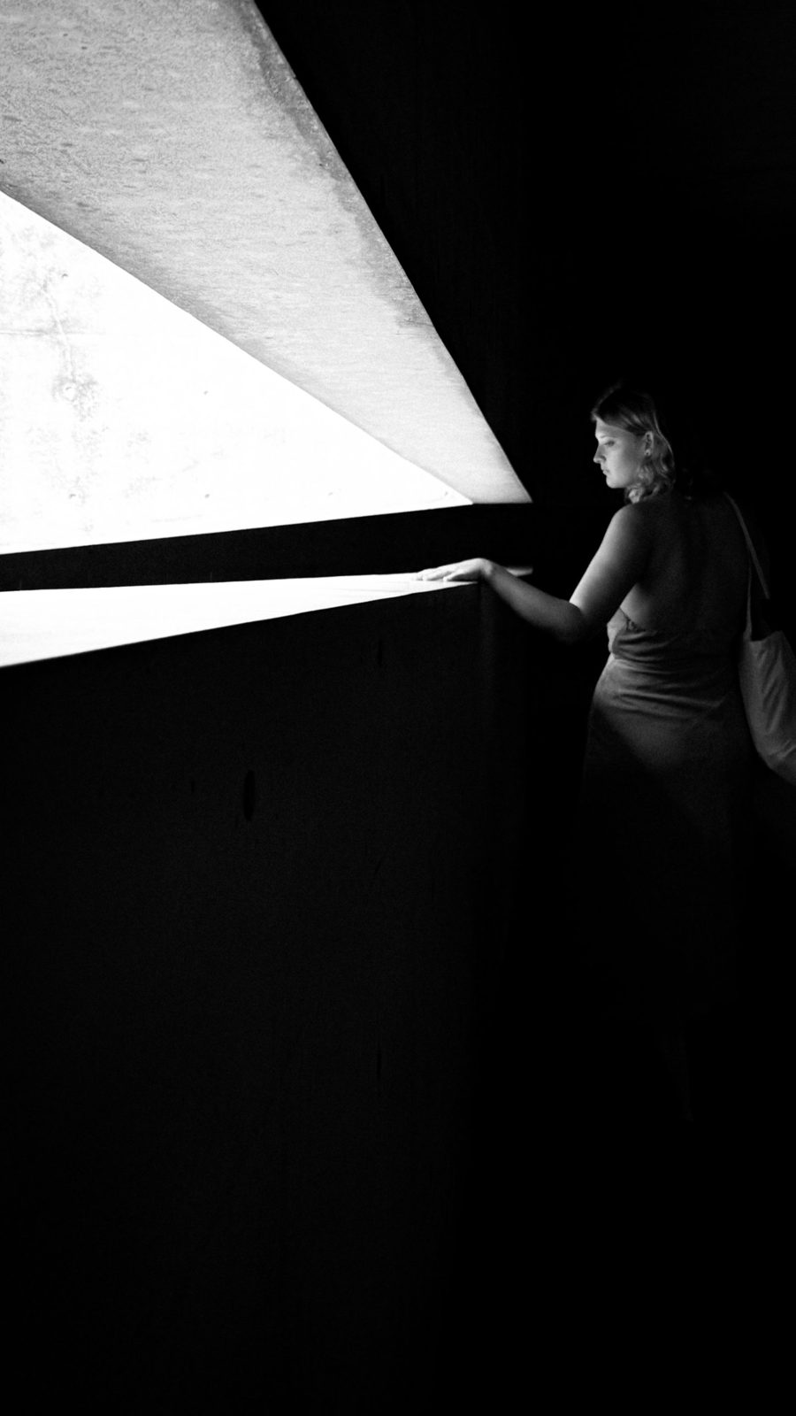 Woman beside a sharp shaft of light, black and white