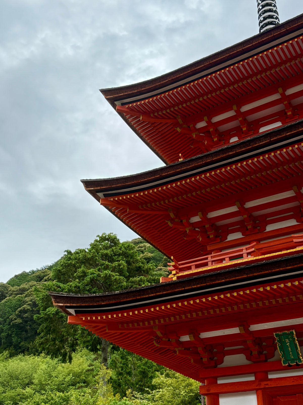 Tiers of a vermilion pagoda against a grey sky