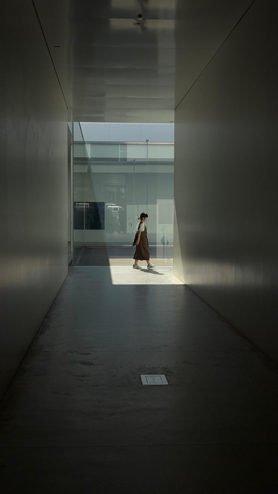 Woman walking past the end of a white corridor
