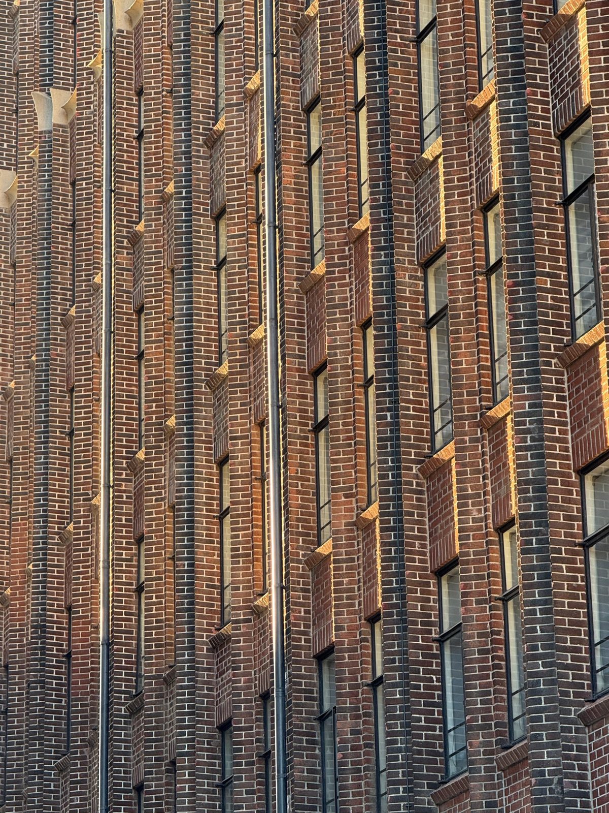 Brick façade with vertical piers and steel windows in warm light